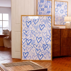 Peut inclure: Trois impressions d'art encadr&eacute;es avec des motifs bleus clairs et blancs. La plus grande impression pr&eacute;sente des c&oelig;urs bleus. Deux petites impressions affichent les mots "XO" et "Happy" avec des smileys. Toutes les impressions ont des cadres en bois.