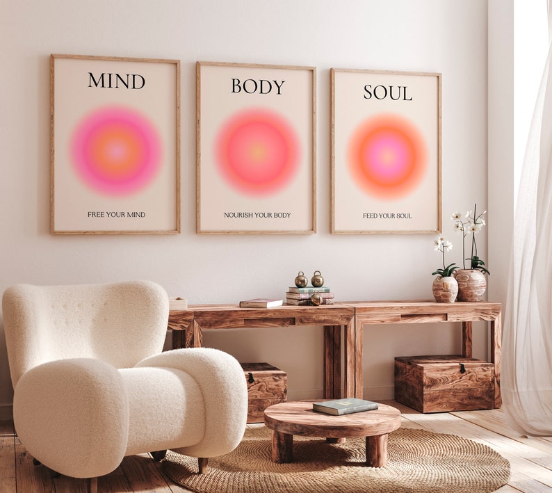 May include: Three framed art prints with the words "MIND", "BODY", and "SOUL" in black text. Each print features a vibrant, circular gradient in shades of pink, orange, and yellow. The text "FREE YOUR MIND", "NOURISH YOUR BODY", and "FEED YOUR SOUL" are below.