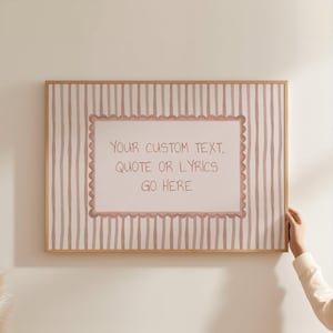 May include: A rectangular wall art print in a light wood frame featuring a vertical striped pattern in muted pink and white. In the center, a scalloped-edge rectangle contains the text: YOUR CUSTOM TEXT, QUOTE OR LYRICS GO HERE.