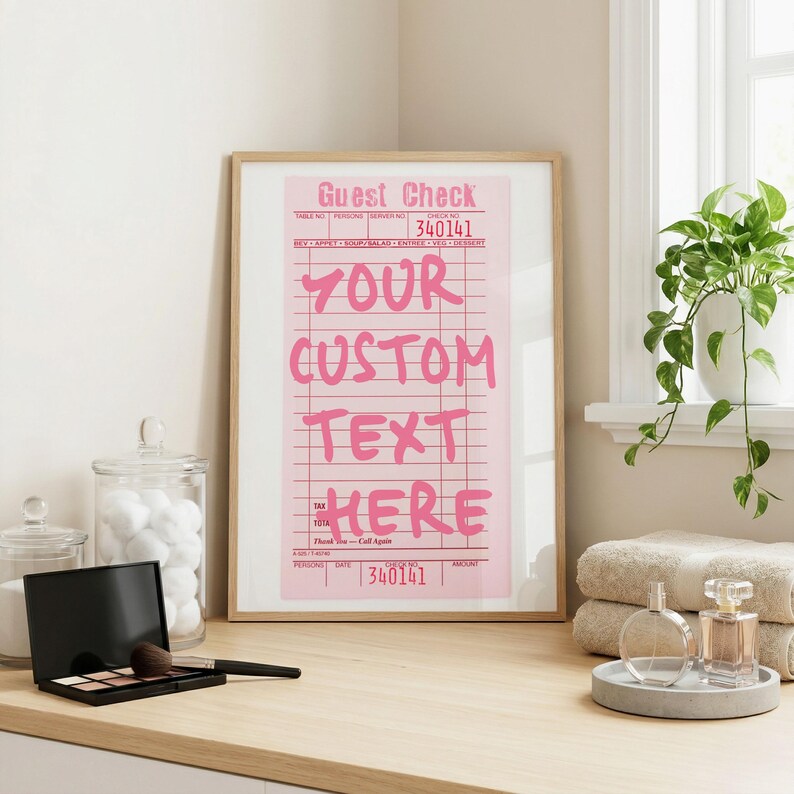 May include: A framed vertical wall art print featuring a pink restaurant guest check design with the text "GUEST CHECK" at the top and "YOUR CUSTOM TEXT HERE" in large pink letters, with the number "340141" printed at the top and bottom.