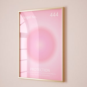 May include: A gold framed poster with a pink background and a white circle in the center. The text "Angel No. 444" is at the top of the poster. The text "PROTECTION" is at the bottom of the poster, along with the text "The universe and your spiritual guides are protecting you. Doors of opportunity will be opened."