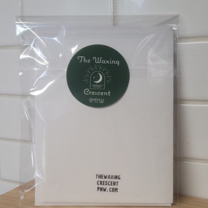 Może przedstawiać: Biała kartka z zieloną okrągłą naklejką. Naklejka przedstawia rosnący księżyc i gwiazdy z tekstem "The Waxing Crescent PNW" w kolorze białym. Na dole kartki znajduje się tekst "THE WAXING CRESCENT PNW.COM" w kolorze czarnym.