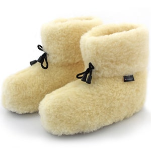 Può includere: Un paio di pantofole in pelle di pecora color crema con lacci neri. Le pantofole hanno una consistenza morbida e soffice e sono realizzate in 100% lana.