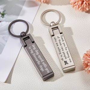 Könnte beinhalten: Zwei silberne Schlüsselanhänger mit gravierten Botschaften. Der Schlüsselanhänger links sagt "Any day spent with you is my favorite days." Der Schlüsselanhänger rechts sagt "Thank you for being one of those rare people who are willing to go."