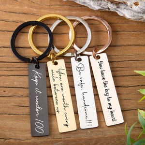 May include: Four silver keychains with different engraved messages: "You have the key to my heart", "Be safe. Handsome!!!", "You are worth every mile between us", and "Keep it under 100".
