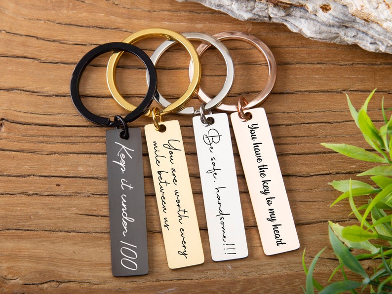 May include: Four silver keychains with different engraved messages: "You have the key to my heart", "Be safe. Handsome!!!", "You are worth every mile between us", and "Keep it under 100".