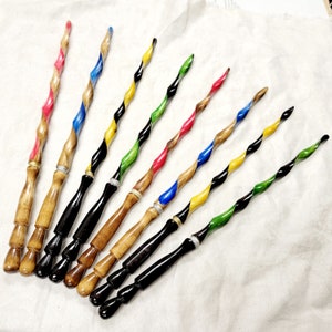 May include: A set of nine wooden wands with colorful, swirling paint designs. The wands are approximately 30 cm long and have a pointed tip.