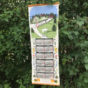 Calendar / Almanac in fabric from the year 1987 with a printed Swedish motif.