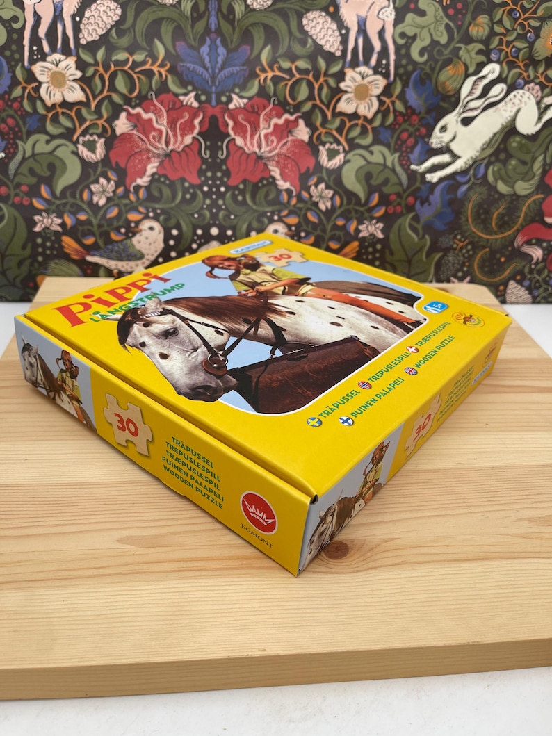 May include: A yellow square box for a 30-piece wooden puzzle featuring Pippi Longstocking riding a white horse with brown spots. The box lid displays the title Pippi L&aring;ngstrump, the number 30, and the Egmont logo, with text in multiple languages.
