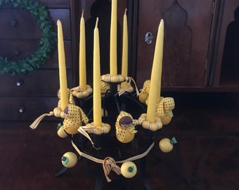 Puede incluir: Un candelero amarillo con seis velas amarillas y decoraciones de muñecas amarillas y negras.