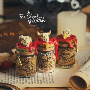 May include: Three decorative jars with skull-shaped lids and red wax seals. The jars are labeled "Loky Blue", "Pinky Heaven", and "Yellow Garden". The jars are on a table with a book, a magnifying glass, and a scroll.