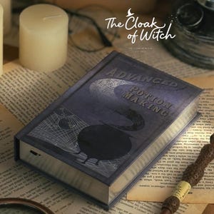 Peut inclure: Un livre rectangulaire intitulé Advanced Potion Making avec une couverture bleu foncé ornée d'un chaudron noir, de lignes géométriques et d'un croissant de lune. Une baguette brune texturée au manche clair repose en diagonale sur le livre.