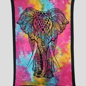 以下が含まれることがあります： 鮮やかなタイダイのブランケットで、詳細な黒い象のデザインが特徴です。象は、ピンク、黄色、青、紫の色合いのカラフルな背景に配置されています。ブランケットには黒い縁があり、デザインに明確なエッジを追加しています。