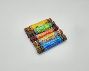 Peut inclure: Plusieurs paquets de bâtonnets d'encens avec des étiquettes colorées. Les étiquettes indiquent "Himalayan Tara Incense", "Himalayan Tsering Incense", "Himalayan Wind Horse Incense" et "Himalayan Purification Incense". Chaque paquet est maintenu par un élastique.