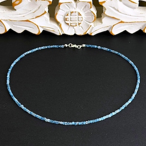 Peut inclure: Un collier délicat composé de petites perles de pierres précieuses bleu clair à facettes disposées en un seul brin. Le collier présente un mécanisme de fermoir argenté au centre du dos, reliant les deux extrémités de la chaîne circulaire perlée.