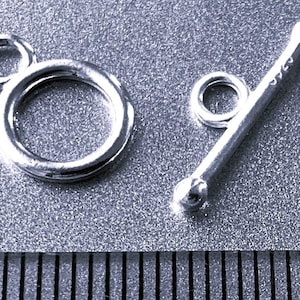 May include: Silver toggle clasp with a round loop and a straight bar with a round loop at one end. The clasp is used for jewellery making.