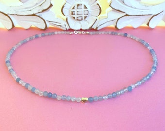 May include: A delicate necklace made with light blue and white beads, featuring a small gold heart charm.