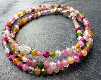 May include: A multi-strand bracelet composed of small, faceted, multicolored tourmaline beads in shades of pink, yellow, green, and clear. The bracelet features a polished silver-toned heart-shaped charm and a silver-toned lobster claw clasp.