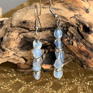 May include: A pair of silver dangle earrings with iridescent blue and white beads and clear rhinestones.