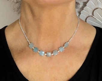May include: A delicate necklace with a silver chain and light blue square-shaped beads.