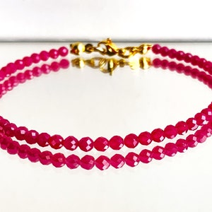 Op de afbeelding: Een armband met twee rijen roze facetgeslepen kralen met een gouden sluiting.