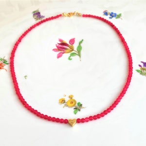 May include: A pink beaded necklace with a gold heart charm.