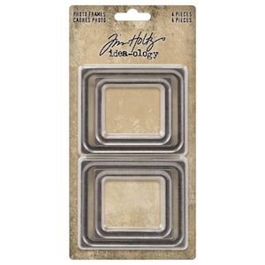 May include: A set of four silver metal photo frames, each with a square shape and a slightly raised edge. The frames are nested inside each other, creating a layered effect. The packaging features the text "Photo Frames" and "Jim Holtz idea-ology".