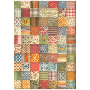 Op de afbeelding: Een patchwork quiltontwerp met een verscheidenheid aan bloemige, geometrische en gepatroneerde stoffen in tinten rood, blauw, groen, bruin, oranje en geel. De quilt bevat een zonnebloem, een vlinder en een lieveheersbeestje.