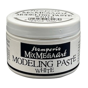 Op de afbeelding: Een witte pot Stämperie Mix Media Art Modeling Paste. De pot heeft een wit deksel en een zwart etiket met witte tekst "MODELING PASTE WHITE". De pot bevat 150 ml pasta.