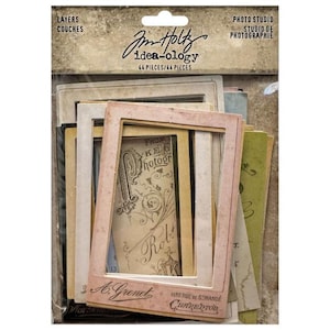 May include: A package of vintage-style photo studio layers. The package includes various paper frames, cards, and ephemera in shades of cream, pink, and green. The text "Jim Holtz idea-ology" and "44 pieces" are visible.