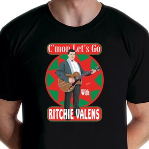 May include: Black t-shirt with a red, green, and white circular design featuring a cartoon image of Ritchie Valens playing a guitar. The text "C'mon Let's Go with Ritchie Valens" is printed on the shirt.