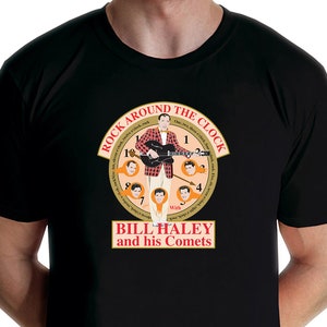 May include: Black t-shirt featuring a graphic of Bill Haley and his Comets. The design includes a clock face with the words "Rock Around the Clock" and images of the band members. The shirt is a classic crew neck.
