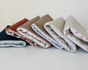 May include: Six folded fabric squares with a variety of patterns and colors. The squares are made of corduroy and have a floral print on the inside.