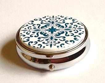 Small round pillbox decorated in polymer clay, blue cement tile style on a white background