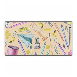 Peut inclure: Un tapis de souris coloré avec un motif de fournitures scolaires, y compris des crayons, des crayons de couleur, des trombones, une règle, un pinceau et une pomme. Le fond est de couleur beige clair.
