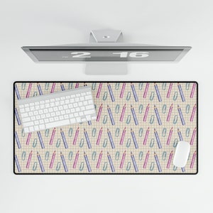 Peut inclure: Tapis de bureau rectangulaire avec un motif répété de crayons violets et roses et de trombones verts sur un fond quadrillé. Un clavier et une souris blancs sont sur le tapis, avec un écran d'ordinateur au-dessus.