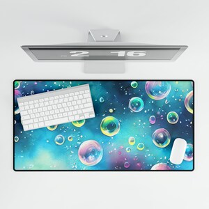 May include: A blue and green desk mat with a pattern of iridescent bubbles. A white keyboard and mouse are on the mat.