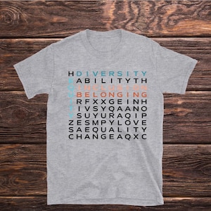 May include: A gray t-shirt with a word search design featuring the words "Diversity", "Ability", "Inclusion", "Belonging", "Respect", "Equality", "Love", "Change", and "Safe".