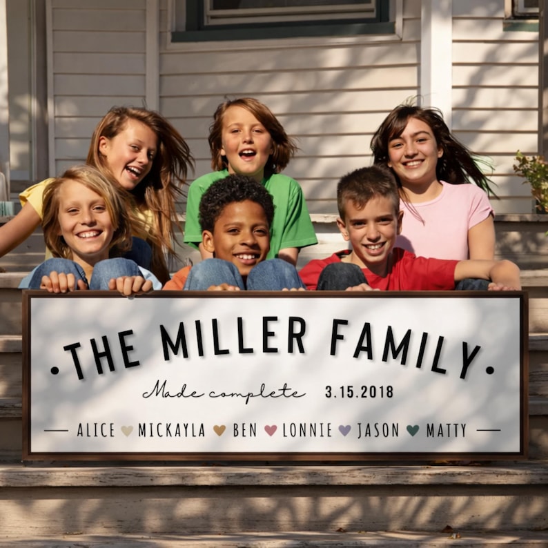 Puede incluir: Un letrero de madera con el texto "THE MILLER FAMILY" en letras negras, con las palabras "Made complete 3.15.2018" debajo. Los nombres de los miembros de la familia se enumeran debajo de la fecha. Seis ni&ntilde;os sonrientes son visibles detr&aacute;s del letrero.