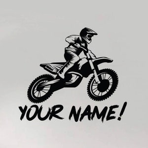 Peut inclure: Silhouette noire et blanche d'un pilote de motocross sautant sur une moto tout-terrain avec le texte "YOUR NAME!" en dessous.