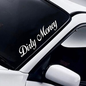 May include: A white car windshield with a white vinyl decal that reads "Dirty Money".