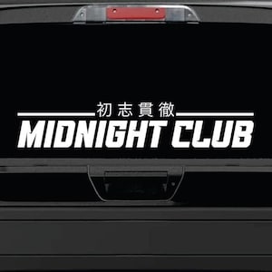 May include: White vinyl decal with the text "MIDNIGHT CLUB" and Japanese characters above it. The decal is on the back window of a black pickup truck.