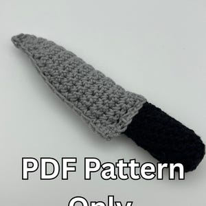 May include: A crocheted knife with a gray blade and a black handle. The text "PDF Pattern Only" is written below the knife.