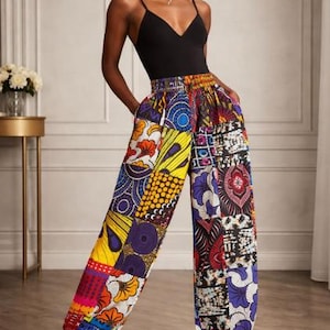May include: A black spaghetti strap top paired with patchwork print pants. The pants feature a vibrant mix of colors and patterns, including yellow, red, blue, and purple. The pants have a high waist and a relaxed fit.