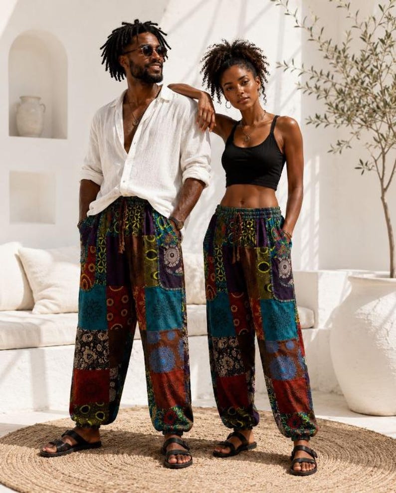 May include: Loose-fitting trousers featuring a patchwork design with various colourful patterns in shades of blue, red, green, and brown. The trousers have an elastic waistband with a drawstring, side pockets, and gathered elastic cuffs at the ankles.