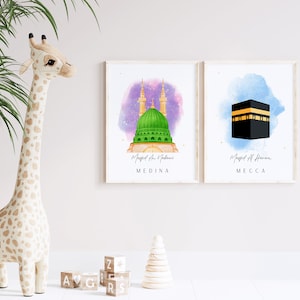 May include: Two watercolor prints of mosques in Medina and Mecca. The print on the left shows the Masjid an Nabawi mosque in Medina with a green dome and two minarets. The print on the right shows the Masjid al-Haram mosque in Mecca with a black cube.