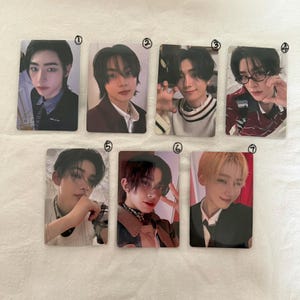 May include: Seven rectangular photo cards featuring portraits of young individuals with various hairstyles and clothing styles, including blazers, sweaters, and patterned shirts. Each card is numbered from one to seven in black ink at the top right corner.
