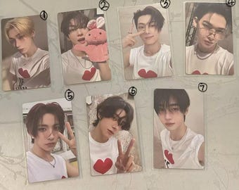 Puede incluir: Una colección de siete tarjetas fotográficas con jóvenes. Cada tarjeta muestra a una persona diferente, todos con una camiseta blanca con un diseño de corazón rojo. Algunas tarjetas muestran a los sujetos haciendo gestos con las manos o usando accesorios.