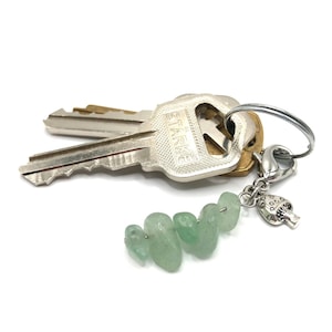 May include: A silver key chain with a silver mushroom charm and a strand of light green jade stones.