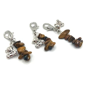 Op de afbeelding: Drie zilveren bedels met bruine tijgeroogstenen en zilveren berenbedels.